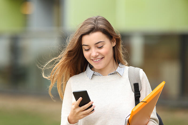 Woman student walking looking at phone