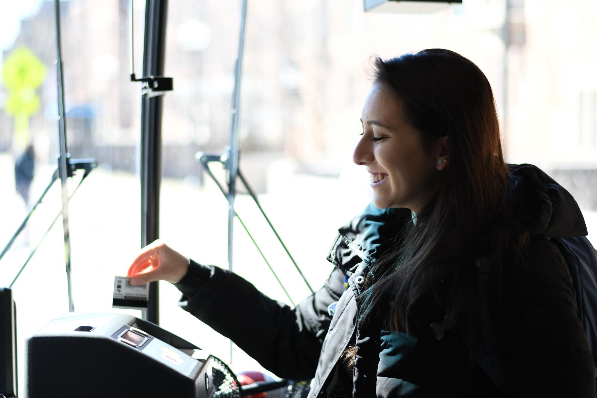 A woman swipes her bus pass as she enters the bus.
