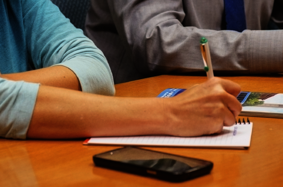 Person with pen, paper, and phone at work