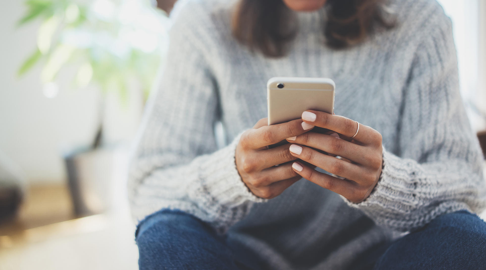 Woman in sweater looking at phone screen