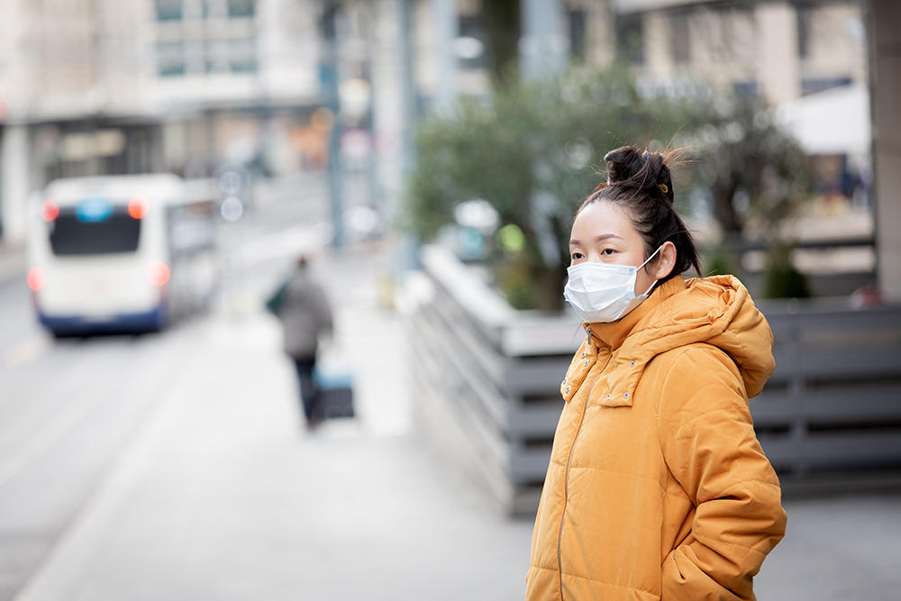 Asian woman wearing mask waiting for bus