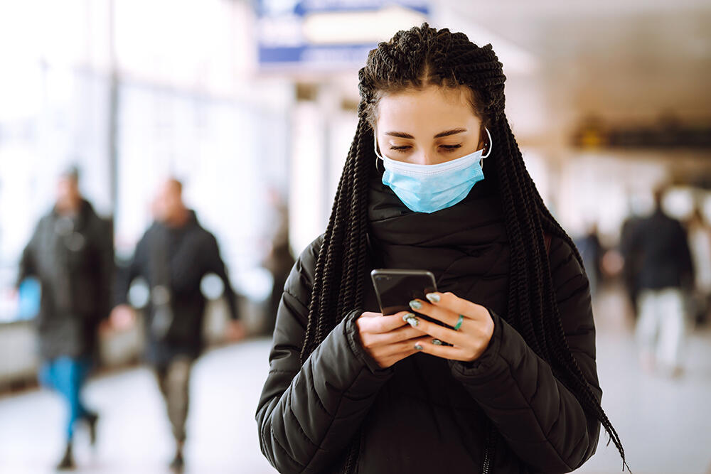 woman wearing mask looking at phone inside building