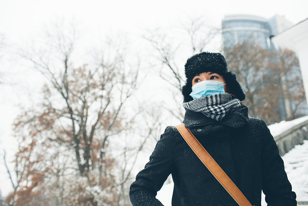 woman wearing mask winter coat on campus