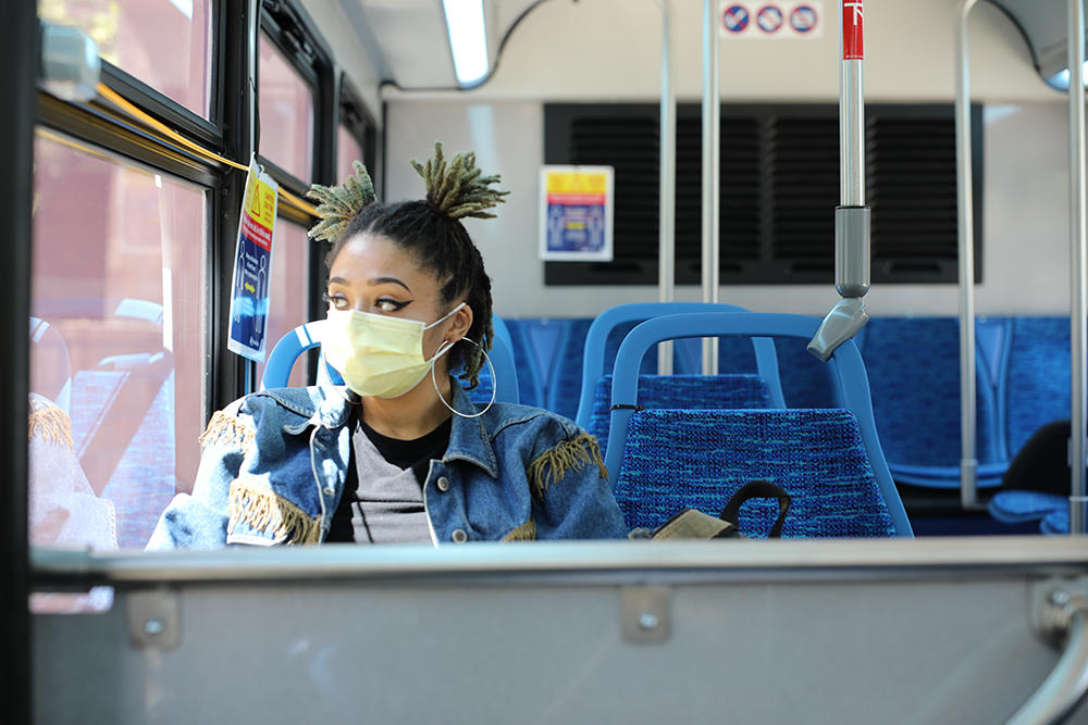African American woman wearing mask riding bus
