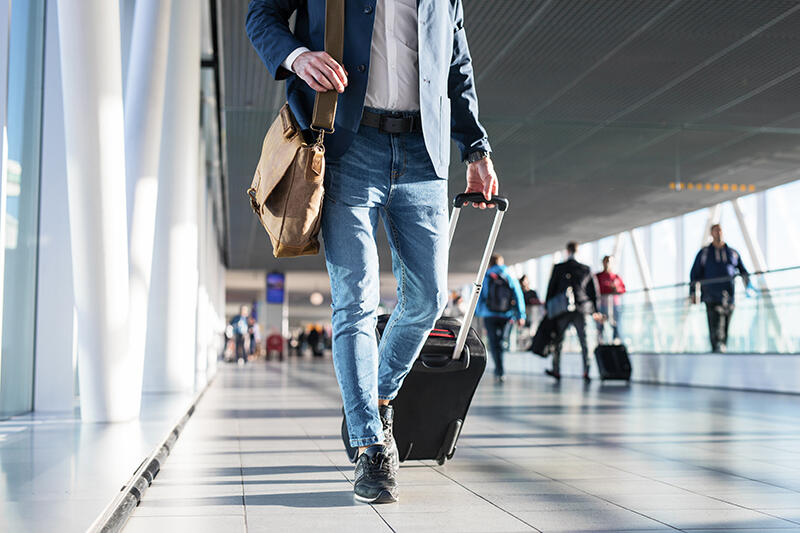 Man walking with carry on suitcase at airport