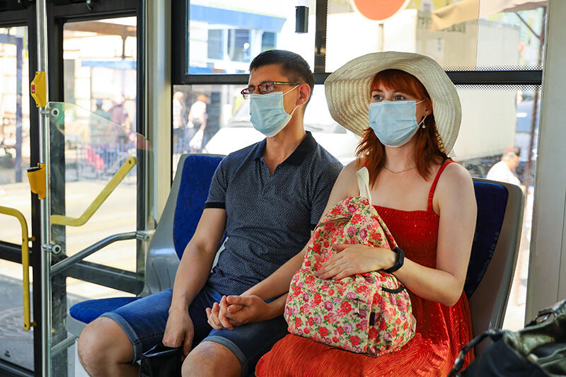 Couple holding hands wearing masks riding the bus