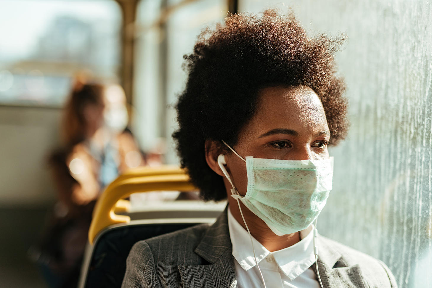 Woman on bus, wearing mask.