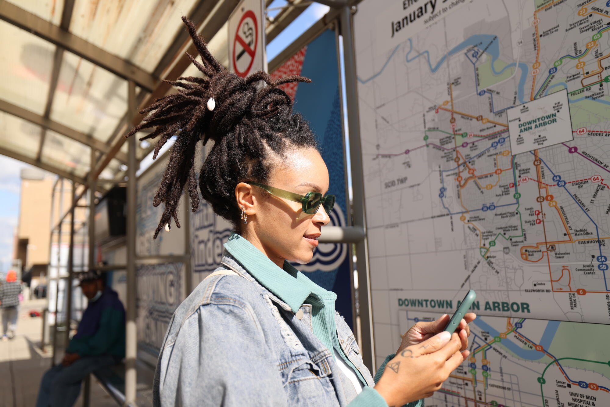 women at bus stop looking at phone