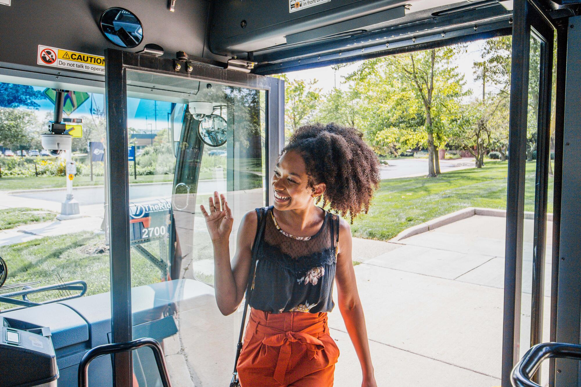 rider waving to driver as boarding bus