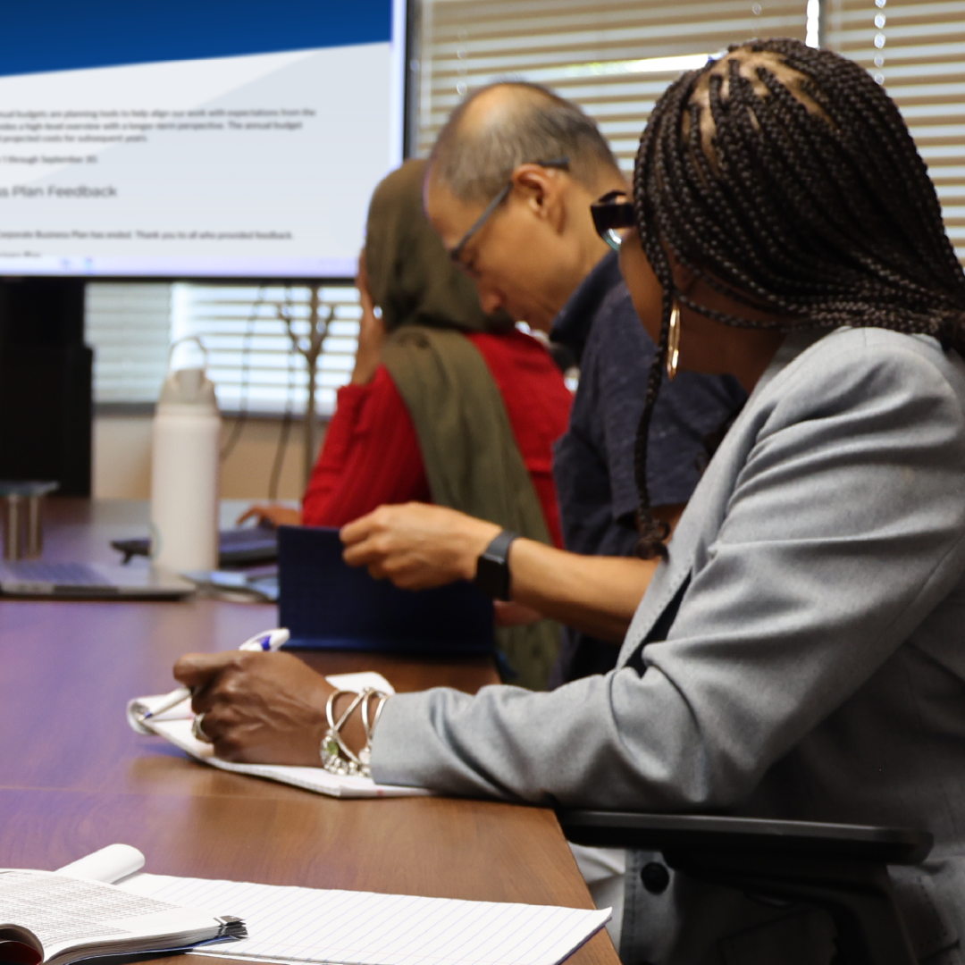 3 people at a table looking at a screen