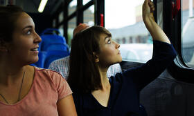 A woman pulls the cord to let the bus driver know she needs to get off the bus at the next stop.