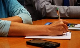 Person with pen, paper, and phone at work