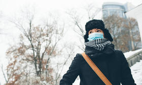 woman wearing mask winter coat on campus