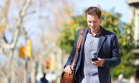 Man walking with messenger bag looking at phone