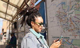 women at bus stop looking at phone