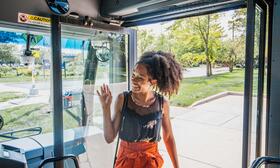 rider waving to driver as boarding bus