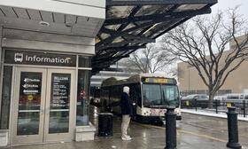 Man waiting outside the Blake Transit Center, bus in the background